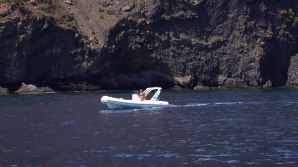 L'homme sur un runabout gonflable flotte le long de la montagne de l'île de Lipari, mer Méditerranée. Journée ensoleillée d'été. Sicile, Italie — Video