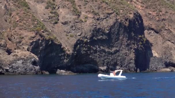 Mężczyzna na nadmuchiwanym promie pływa wzdłuż góry Lipari Island, Morza Śródziemnego. Letni słoneczny dzień. Sycylia, Włochy — Wideo stockowe