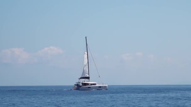 Белая парусная лодка с туристами на борту, плывущими через Средиземное море. Острова Липари. Сицилия, Италия. Горизонт, голубое небо — стоковое видео