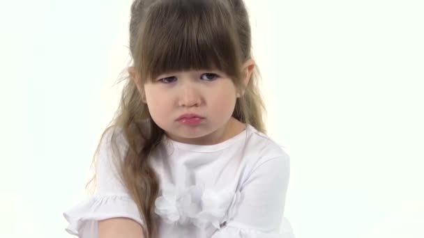 Menina bonito soprou para fora suas bochechas e sentado ofendido no fundo branco. Emoção infantil. Movimento lento. Fechar — Vídeo de Stock