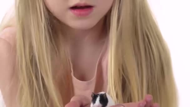 Egy hosszú szőke hajú kislány dekoratív patkányt tart fehér háttérben. Lassú mozgás. Közelről. — Stock videók