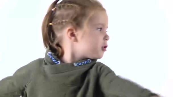 Bambina con le trecce è frolicing e filatura su sfondo bianco. Emozioni infantili. Al rallentatore. Da vicino. — Video Stock