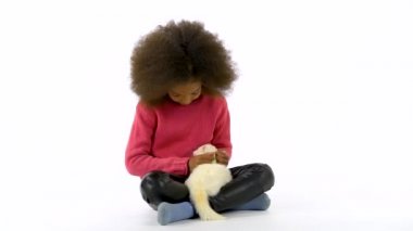 Küçük Afrikalı kız beyaz arka planda kırmızı gözlü albinos dağ gelinciği Furo 'yu okşuyor. Kapatın. Yavaş çekim