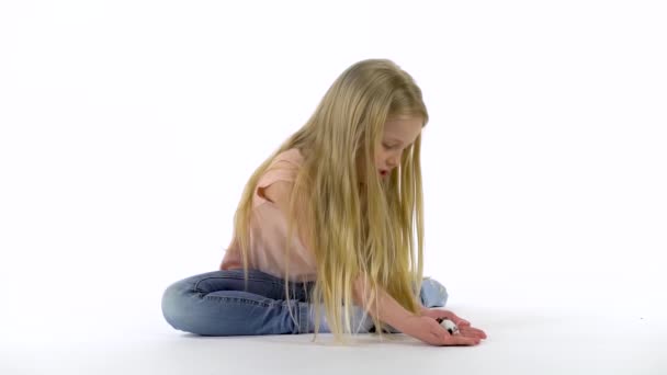 Menina com cabelo loiro longo está segurando rato decorativo no fundo branco. Movimento lento — Vídeo de Stock