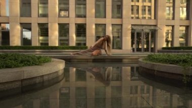 Modern bir şehrin caddesinde dans eden güzel genç kız suya yansıyor. Yavaş çekim