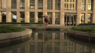Modern bir şehrin caddesinde dans eden güzel genç kız suya yansıyor. Yavaş çekim
