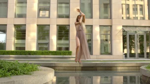 Prachtig jong meisje dansend op de straat van een moderne stad en wordt weerspiegeld in het water. Langzame beweging — Stockvideo