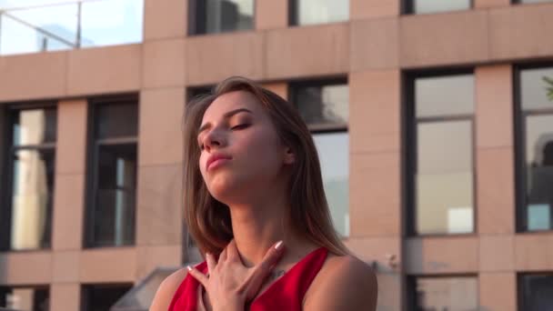 Beautiful young girl dancing on the street of a modern building of a business center in the sunset light. Close up. Slow motion. — Stock Video