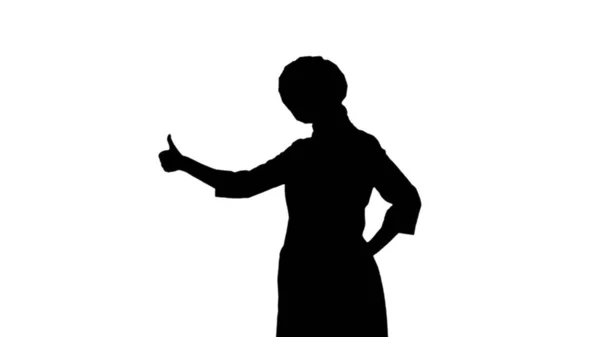 Портрет черного силуэта повара девушки в токе, фартук стоит и показывает, как знак изолирован на белом фоне — стоковое фото