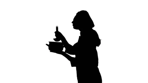 Porträt der schwarzen Silhouette einer Köchin, die in Uniform Gericht probiert. — Stockfoto