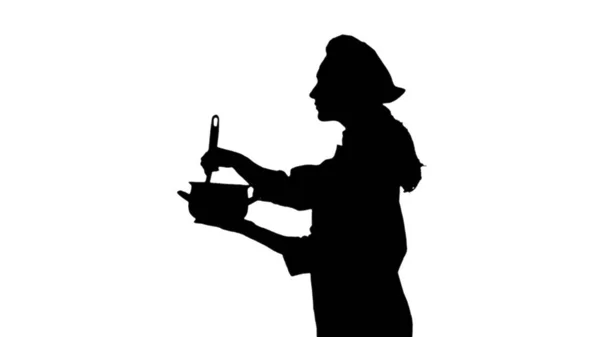 Porträt der schwarzen Silhouette einer Köchin, die in Uniform Gericht probiert. — Stockfoto