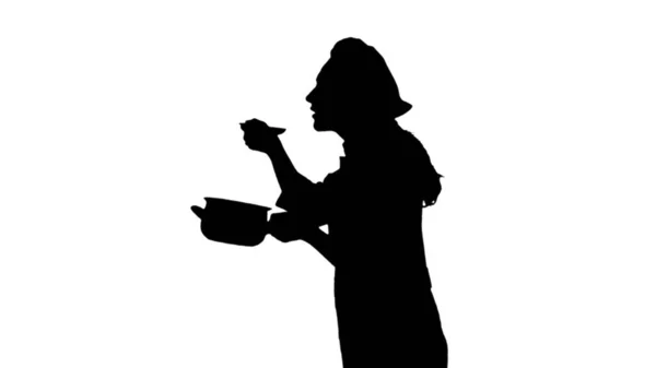 Portrait de silhouette noire d'une cuisinière en uniforme en train d'essayer le plat . — Photo