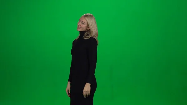 Молода жінка стоїть з ніжною посмішкою. Зелений екран — стокове фото