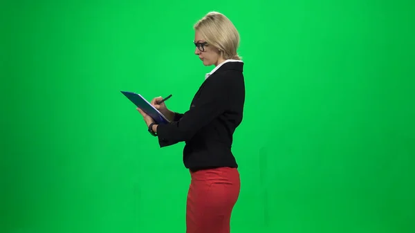ビジネスマンの女性が立っている間にタブレットで何かを書いています。緑の画面 — ストック写真