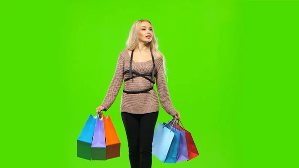 Girl in a beautiful dress carries a lot of multi colored packages. Green screen — Stock Photo, Image