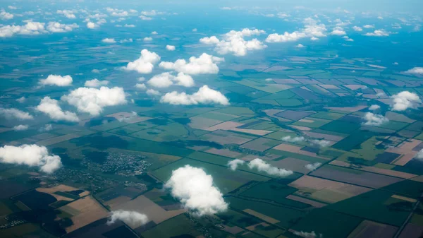 Fotografía aérea de un patrón de campos, valles y aldeas con cielo nublado sacado de un avión —  Fotos de Stock