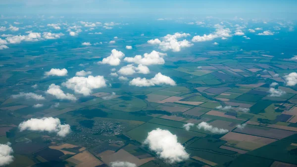 Fotografía aérea de un patrón de campos, valles y aldeas con cielo nublado sacado de un avión —  Fotos de Stock