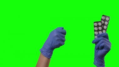 Doktor hapları gösteriyor ve jestler yapıyor. Korumalı mavi eldivenli kadın elleri yeşil ekrana yakın çekim yapıyor..