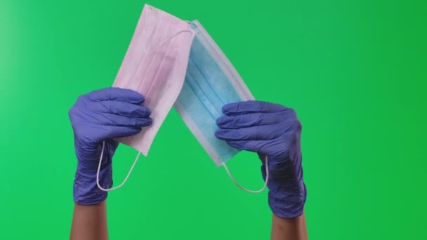 Doctor mostrando mascarillas respiratorias sosteniendo equipos en sus manos protegidos por guantes médicos azules. Pantalla verde. De cerca. . — Vídeo de stock