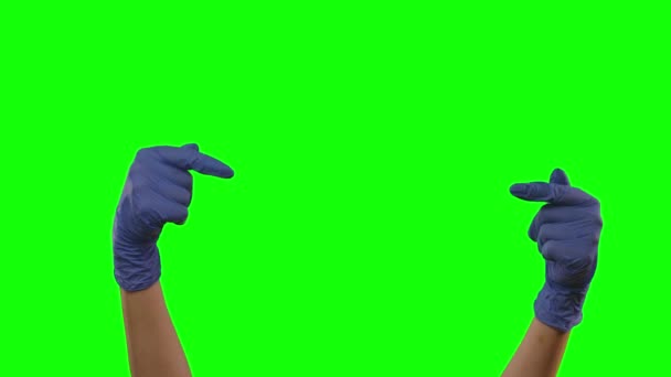 Handen in blauwe handschoenen gebaren met wijzende wijsvingers op iets met kopieerruimte. Groen scherm. Sluiten. — Stockvideo