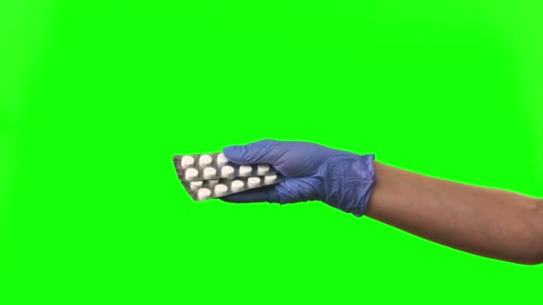 医生展示药丸。女性手戴蓝色防护手套在绿色屏风处特写. — 图库视频影像