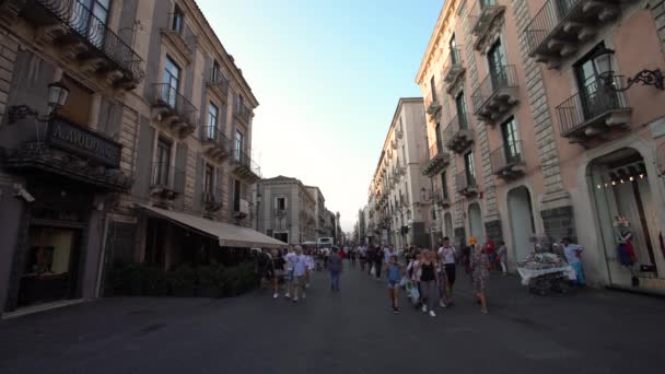 CATANIA, SICILIA, ITALIA - SEPTIEMBRE, 2019: Multitud de turistas caminando por calles rodeadas de antiguos edificios históricos, cafeterías y tiendas. Cielo azul — Vídeos de Stock