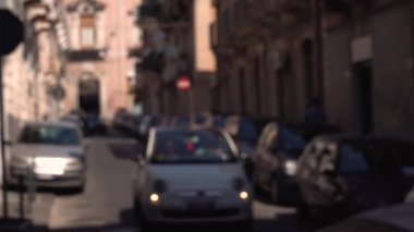 CATANIA, SICILY, ITALY - Eylül 2019: Bulanık hareket, dar işlek cadde. Eski binalar. Park ve hareket halindeki arabalar. Yürüyen turistler