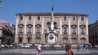 CATANIA, SICILY, ITALY - SEPT, 2019: Fil Sarayı 'na karşı meydanın ortasında duran fil heykeli. Yürüyen turistler, mavi gökyüzü