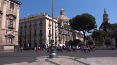 CATANIA, SICILY, ITALY - SEPT, 2019: heykelleri ve sütunları olan Roma Katolik katedrali. Etrafı tarihi binalarla çevrili. Yürüyen turistler. Mavi gökyüzü