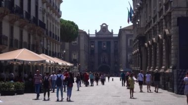 CATANIA, SICILY, ITALY - SEPT, 2019: Antik tarihi binalar ve kafe terası ile çevrili meydanda yürüyen turistler. Güneşli gün, mavi gökyüzü