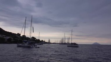Akdeniz 'e demir atmış yelkenli gemiler. Dağ, ağaçlar ve binalar. Lipari Adaları, Sicilya, İtalya