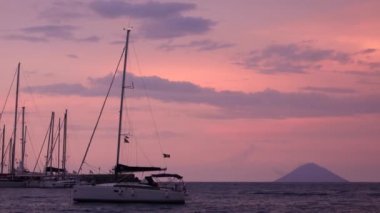 Akdeniz 'de Lipari Adaları' na ve renkli gökyüzüne demir atmış beyaz yelkenli tekneler. Sicilya, İtalya