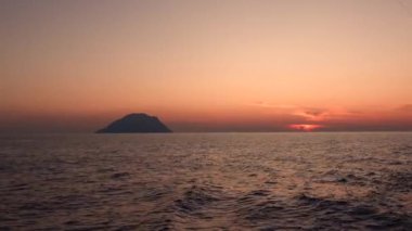 Akdeniz 'deki Lipari Adası ufka karşı. Renkli gökyüzü, yaz gün batımı ya da gün doğumu. Dalgalanan su yüzeyi. Sicilya, İtalya