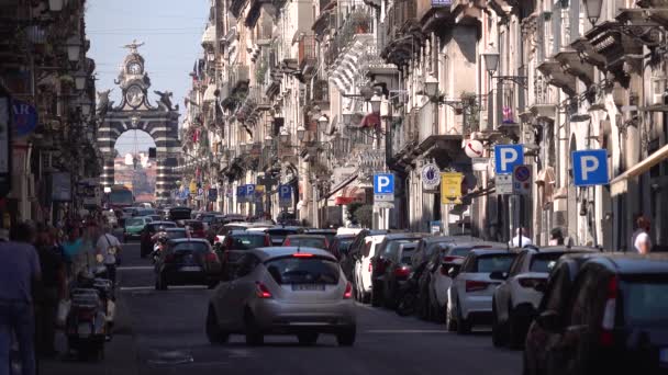 CATANIA, SICILIA, ITALIA - SEPTIEMBRE, 2019: Blusy street with view on Gate of Giuseppe Garibaldi. Edificios antiguos con tiendas. Tráfico, turistas ambulantes — Vídeos de Stock