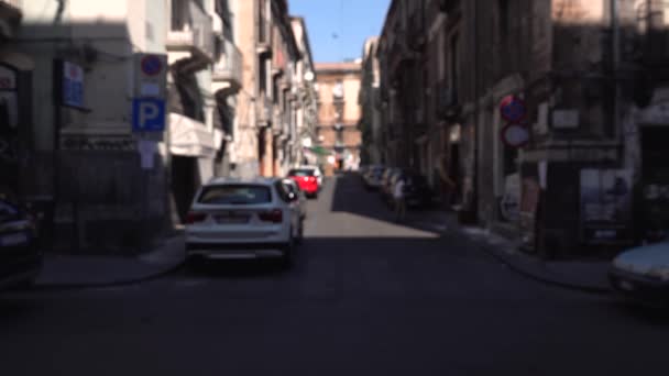 KATANIA, SICILY, WŁOCHY - WRZESIEŃ, 2019: Niewyraźne poruszenie, zamiatająca kobieta ulica. Stare budynki z balkonami. Zaparkowane i poruszające się samochody. Turyści spacerujący — Wideo stockowe