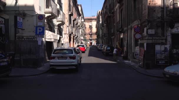 CATANIA, SICILY, ITALY - SEPT, 2019: Woman sweeping street. Old buildings with balconies. Parked and moving cars. Walking tourists — Stock Video