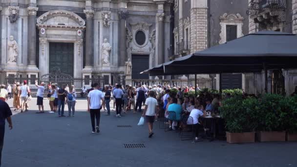 KATANIE, SICILIE, ITÁLIE - SEPT, 2019: Terasa kavárny proti římskokatolické katedrále se sochami, sloupy, zdobená fasáda. Chodící turisté — Stock video