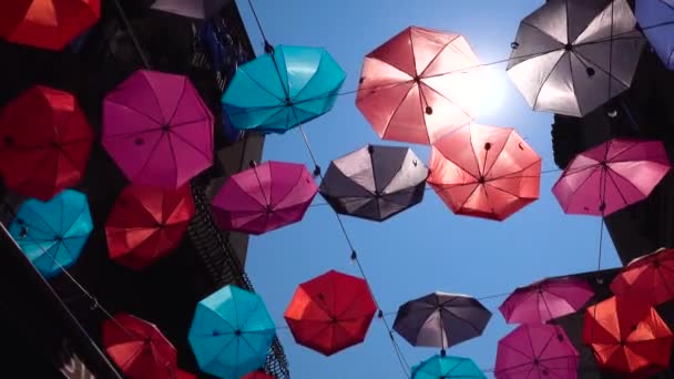 Красочные зонтики, висящие на веревке между старыми зданиями, колеблющиеся от ветра. Голубое небо, яркое солнце в Катании, Сицилия, Италия — стоковое видео