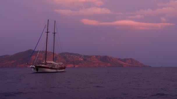 Sailboat anchored in Mediterranean sea against Lipari Island and colorful sky. Sicily, Italy — Stock Video
