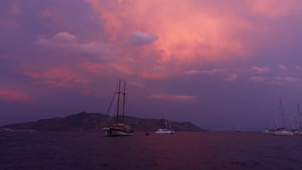 Sailboat and yachts anchored in Mediterranean sea against Lipari Island and colorful sky . Catamaran is floating. Sicily, Italy — Stock Video