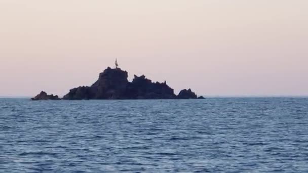 Камені з маяком на вершині Середземного моря проти горизонту. Блакитна поверхня води, чисте небо. Острови Ліпарі, Сицилія, Італія — стокове відео