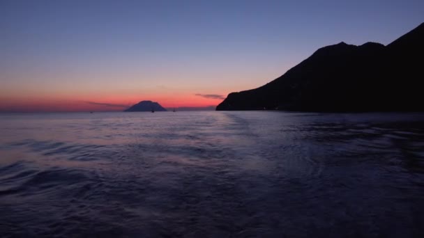 Liparské ostrovy ve Středozemním moři, horizont. Plachetnice a čluny v dálce. Barevné nebe, západ slunce nebo východ slunce. Sicílie, Itálie — Stock video
