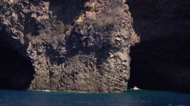 Şişme kayıkta kürek çeken ve Akdeniz 'deki Lipari Adası' nın mağarasında yüzen insanlar. Yaz güneşli bir gün. Sicilya, İtalya