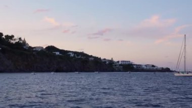 Akdeniz 'de dağa yakın bir yere demir atmış yelkenli gemiler. Yaz batımı. Lipari Adaları, Sicilya, İtalya