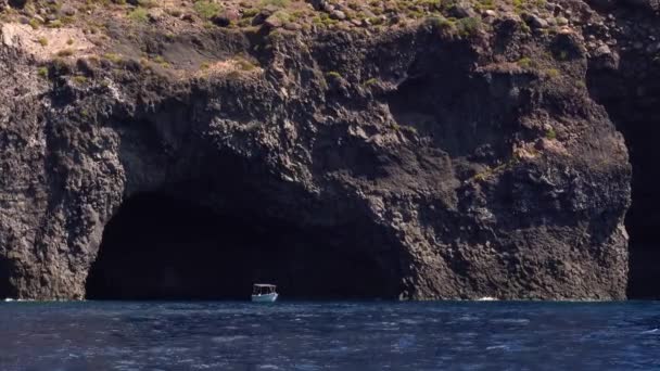 地中海のリパリ島の洞窟の近くに停泊する孤独な白いボート。夏の晴れた日。シチリア島,イタリア — ストック動画