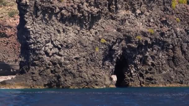 Barco blanco en el mar Mediterráneo, detrás de roca con agujero, isla de Lipari. Día soleado de verano, cielo azul. Sicilia, Italia — Vídeo de stock