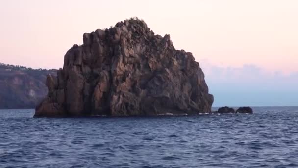 Hög klippa i Medelhavet mot horisonten, färgglad himmel. Sommarsolnedgång eller soluppgång. Lipariöarna, Sicilien, Italien — Stockvideo