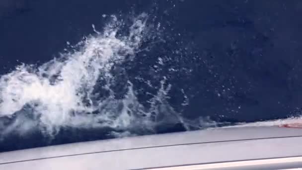 Превышение скорости на белой яхте создает пенные волны на синей поверхности моря — стоковое видео
