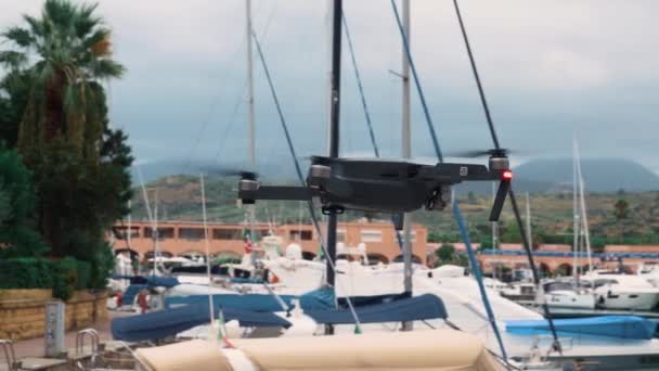 FURNARI, SICILIA, ITALIA - SEPTIEMBRE 2019: Dron negro o cuadrohelicóptero volando en el puerto deportivo Portorosa, Furnari, Italia — Vídeo de stock