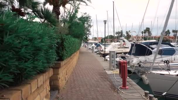 FURNARI, SIZILIEN, ITALIEN - SEPT 2019: Geflieste Promenade an der Seebrücke mit festgemachten Segelyachten und Ausreißern — Stockvideo